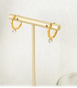 Macro shot of French style gold hoop earrings with sparkling round zircon charms on a stand