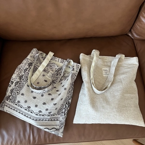 Detail of plain and paisley cotton linen tote bags on a brown leather sofa background