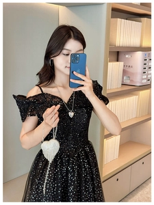 Close-up of heart-shaped rhinestone handbag paired with a black sequin dress