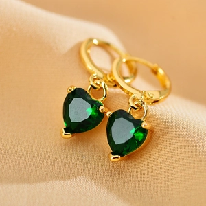 Elegant gold hoop earrings with green heart-shaped zircon pendants on beige background