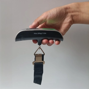 Close-up of portable 50kg digital luggage scale with backlit LCD screen and nylon strap