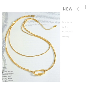 Details einer goldenen Doppelketten-Halskette mit minimalistischem Karabiner-Anhänger