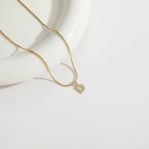 Gold snake chain necklace with sparkling zircon-set letter D pendant on white tray