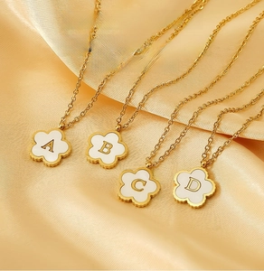 Detailed macro of gold 18K plated stainless steel flower pendants with shell letter inlay
