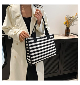 Detail of large striped canvas tote bag showing the metal snap closure and fabric handle
