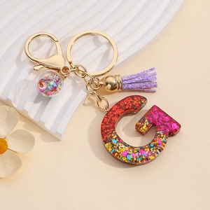 Detail of resin letter G keychain with colorful glitter sequins and purple tassel