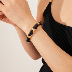 Close-up of a wide French vintage gold and black enamel cuff bracelet worn by a model