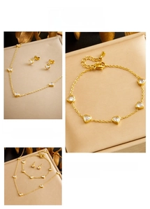 Detailed set of gold-plated necklace, bracelet and earrings with transparent heart gems