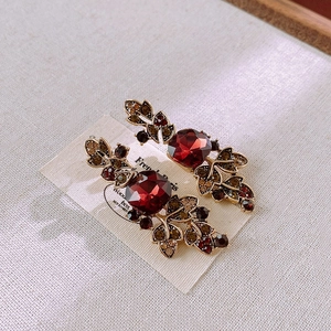 Close-up of vintage hair clip with deep red rhinestone and amber leaf design