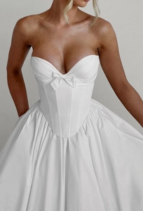 Detailed view of white strapless corset dress with bow decoration and boning structure