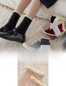 Detail of elegant ribbed cotton socks featuring intricate beige lace trim at the cuff