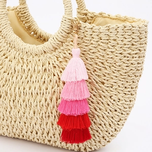 Bohemian gradient pink five-layer tassel charm on a beige woven tote bag with gold clasp