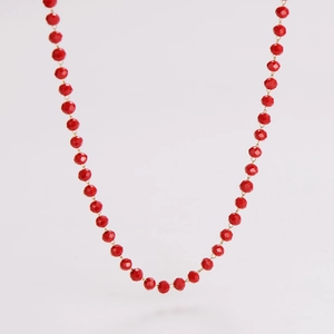 Detail of red faceted beaded necklace with small gold-toned metal connector rings