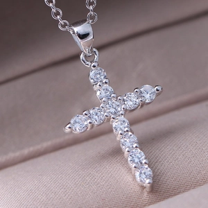 Macro view of a silver S925 cross pendant necklace fully set with white cubic zirconia stones