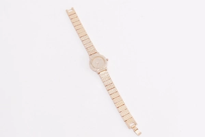 Macro shot of rose gold women's watch with shimmering diamonds on white background