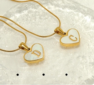 Macro shot of 18K gold plated heart pendants with shell inlay and letters D and C