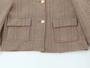 Detailed macro shot of brown houndstooth tweed fabric with ornate gold buttons
