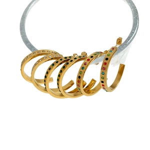 Chunky gold C-shaped earrings set with colorful crystals and rhinestones on a white stand