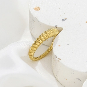 Detailed macro view of gold ribbed twisted ring on stone prop with silk backdrop