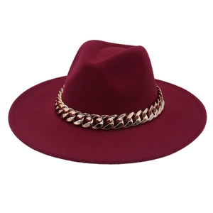 Detail of burgundy fedora hat with a thick gold acrylic chain on smooth wool felt