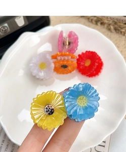 Detailed macro shot of small daisy acetate hair claws in various vibrant colors