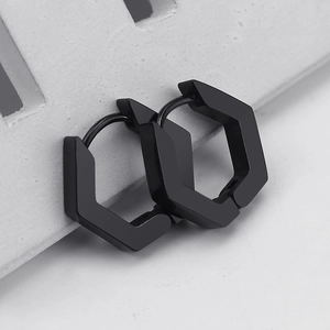 Macro shot of black hexagonal earrings with a matte metallic finish on a grey surface
