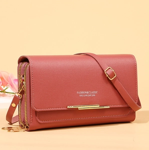 Detail view of red-brown crossbody phone bag with double zippers and gold hardware