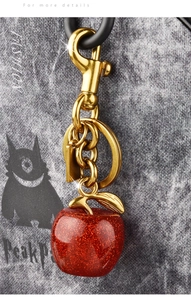 Detailed macro view of the red glitter apple keychain with polished gold metal hardware