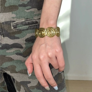 Detail of vintage golden spiral disc bracelet worn on wrist with natural window lighting