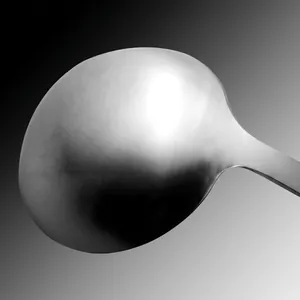 Détail d'une louche en acier inoxydable poli avec une finition miroir lisse et nette