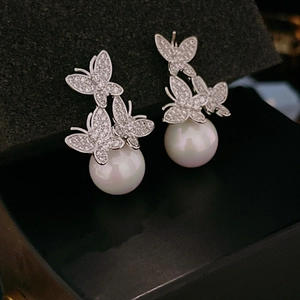 Macro detail of silver butterfly stud earrings with sparkling pavé zircons and pearls