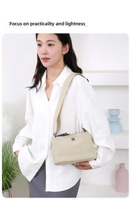 Détail du sac bandoulière en nylon beige clair avec logo fleuri et sangle large