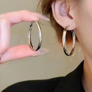 Detailed view of large silver hoop earrings showcasing size and mirror finish shine
