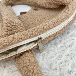 Close-up detail of soft brown plush tote bag showing cute bear pattern and metal zipper