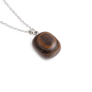 Detailed close-up of a brown tiger eye stone pendant on a silver-colored chain