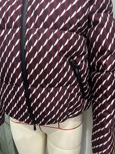 Detail shot of burgundy geometric quilted puffer jacket with durable black zippers