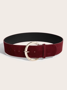 Détail d'une ceinture large en daim bordeaux avec surface texturée et boucle dorée en croissant
