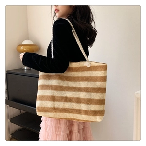 Model wearing large striped woven tote bag with twisted rope handles in a natural room setting