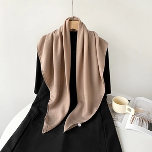 Close-up of lightweight beige cotton linen scarf draped on a black dress hanger