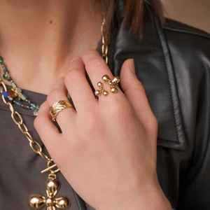 Close-up of gold stainless steel feather ring and stacked necklaces on a model