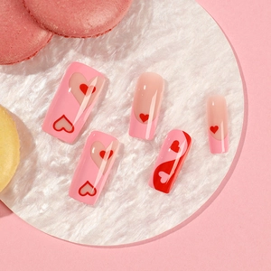 Press-on nails with pink French tips and red heart patterns for Valentine's Day