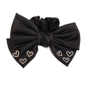 Elegant black satin bow hair tie featuring six sparkling silver rhinestone hearts on white