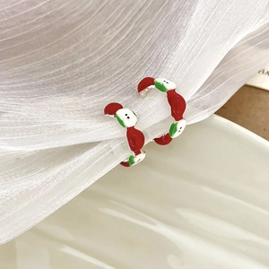 Detailed view of red apple hoop earrings with enamel finish on white pleated fabric