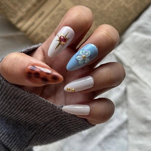 Detailed close-up of 3D cherry almond-shaped press-on nails with floral and heart art