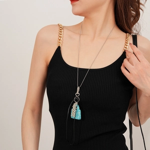 Détail d'un collier avec pendentif sac à main en argent orné de cristaux bleus et blancs