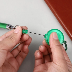 Detail showing green retractable pen with metal carabiner and pull cord function