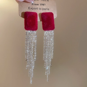 Dettaglio di orecchini quadrati rossi con nappe di strass argento scintillanti