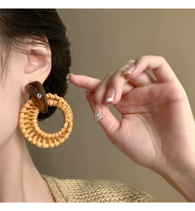 Detail showing vintage resin geometric studs and woven rattan round earrings on a model