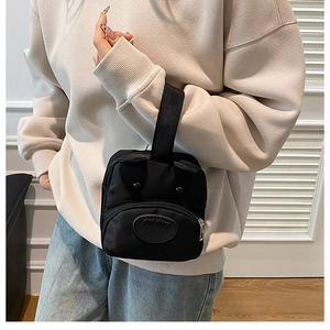 Detailed shot of black cartoon dog handbag with 3D ears and front zipper pocket detail