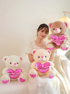 Detailed view of plush teddy bears holding pink metallic love hearts for gift giving